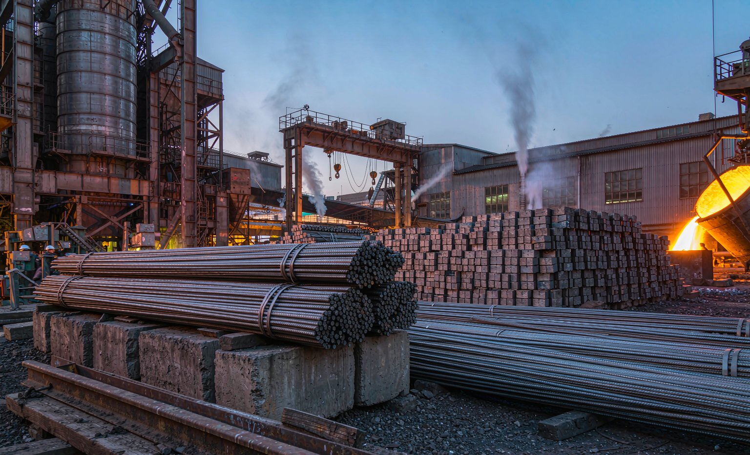 Steel rebar, billets and molten steel at a steel mill at dusk