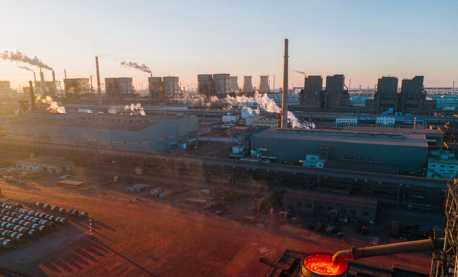 Aerial view of an integrated steel plant at golden hour with molten steel pouring