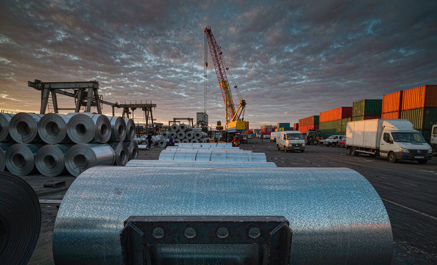 Coils of galvanized steel in an industrial yard at dusk